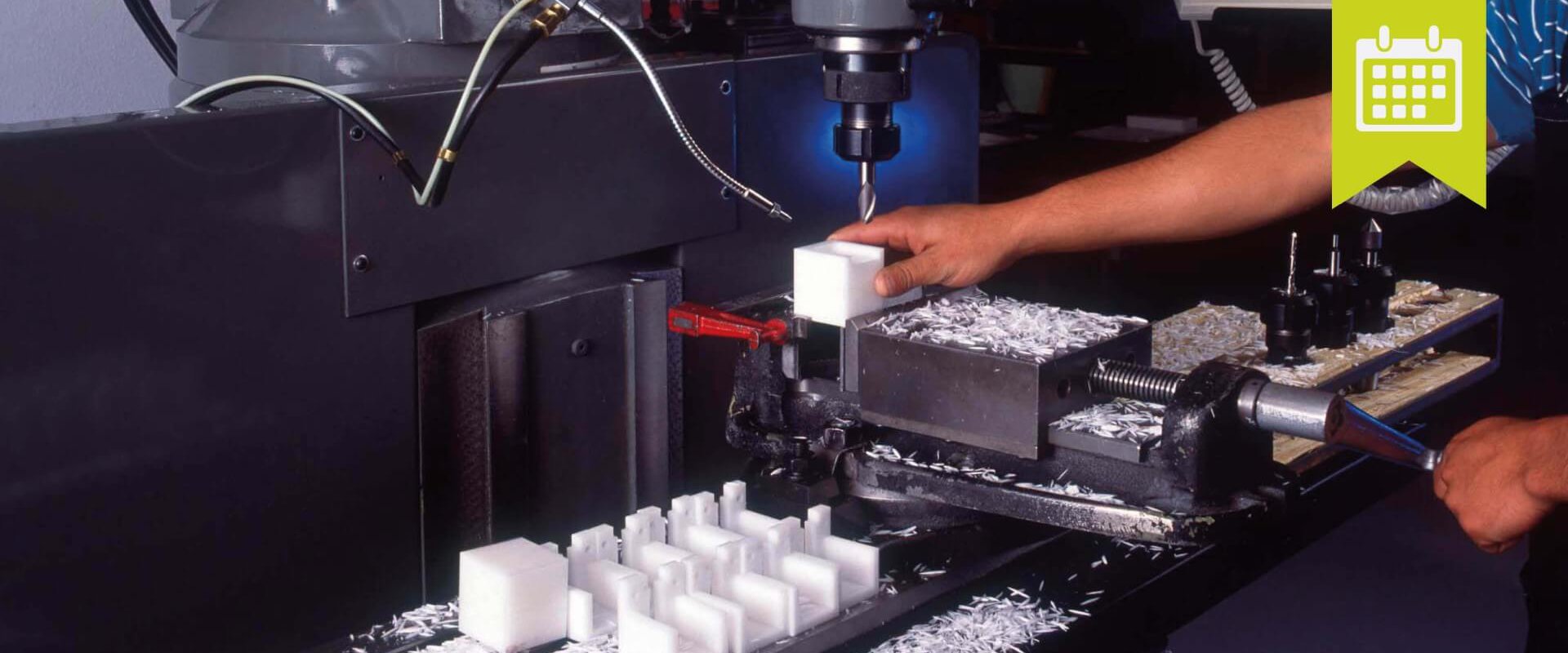 Ein Mann arbeitet an einer Maschine, die weiße Kunststoffwürfel herstellt.